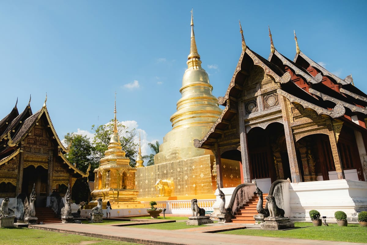 Drevené chrámové budovy a zlatá stupa v Chiang Mai