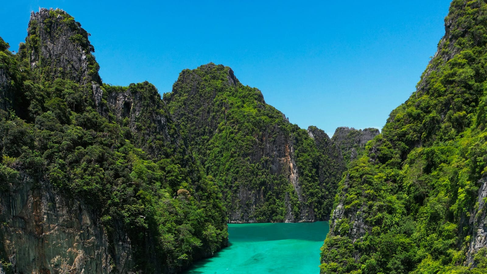 Lode longtail v tyrkysovej lagúne Pi Leh medzi vápencovými skalami v provincii Krabi