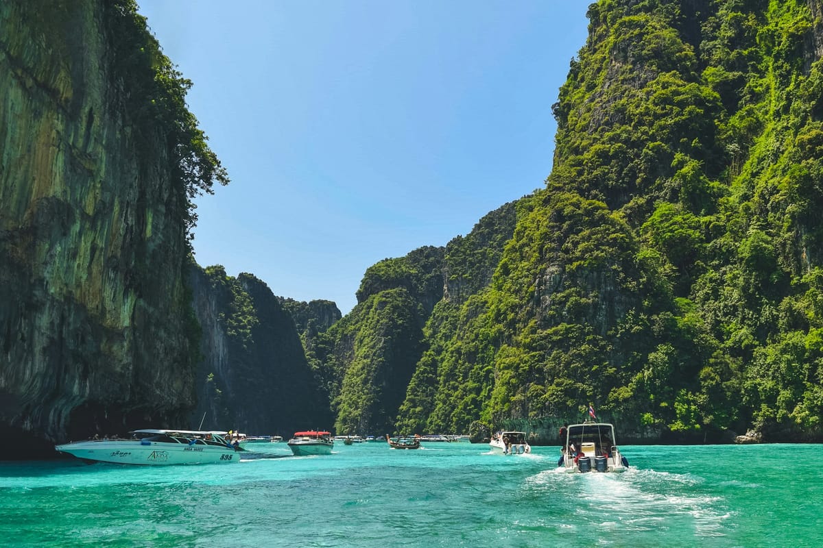 Strmé zarastené útesy a motorové člny v zátoke v provincii Krabi