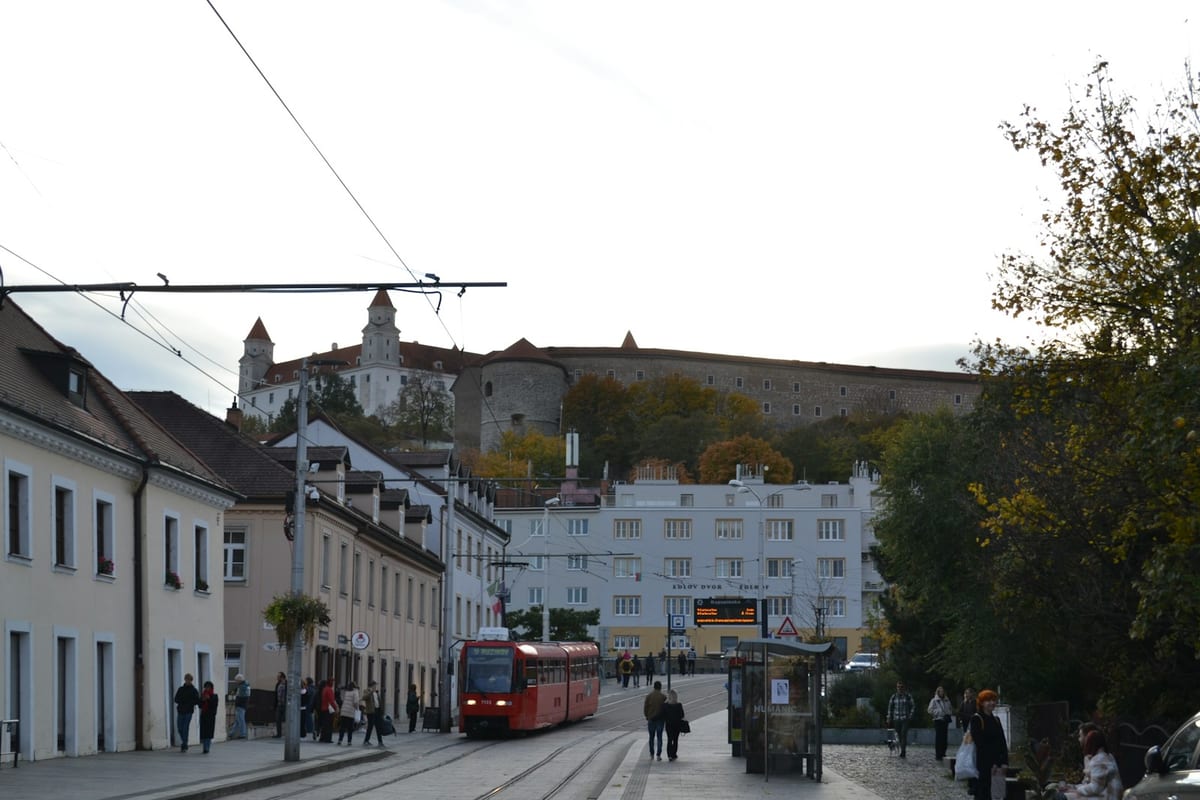 Červená električka na ulici v Starom Meste, nad ňou Bratislavský hrad