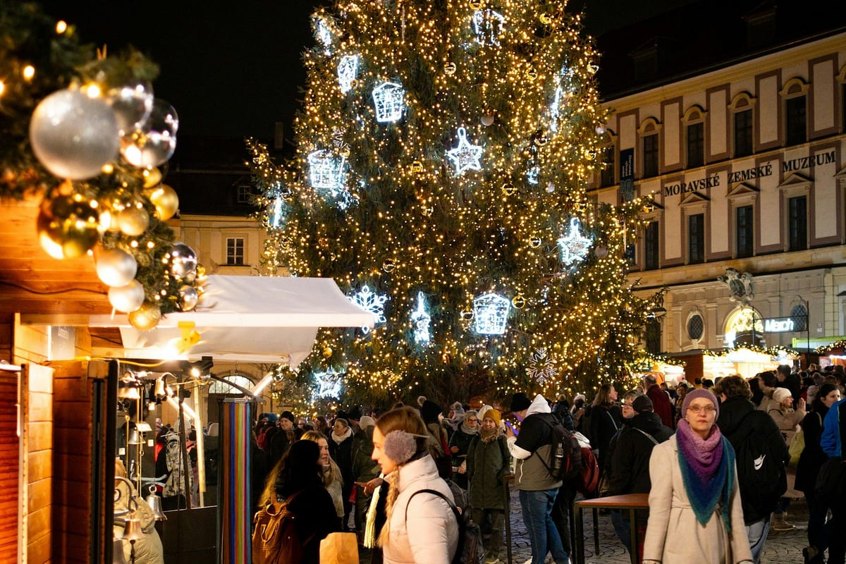 Rozsvietený vianočný strom a stánky na Zelnom trhu v Brne večer, v pozadí Ditrichštejnský palác