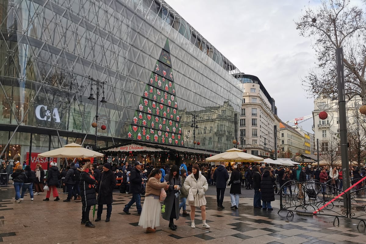 Stánky a ľudia na vianočnom trhu na Vörösmarty tér v Budapešti cez deň