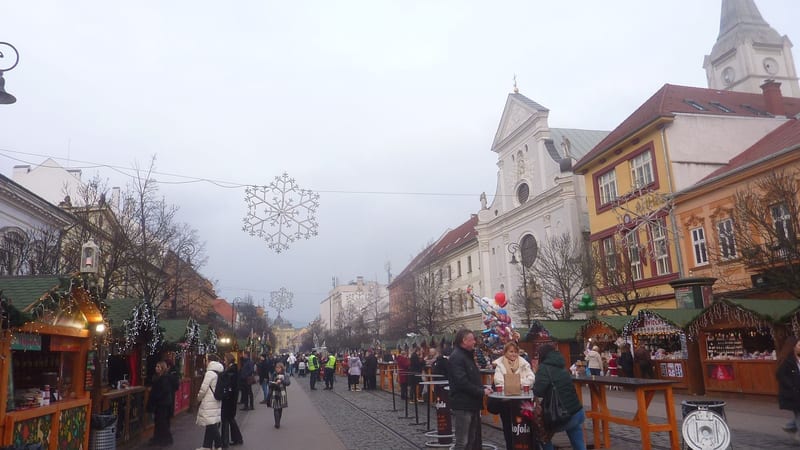 Drevené stánky vianočných trhov na Hlavnej ulici v Košiciach so snehovými vločkami nad ulicou