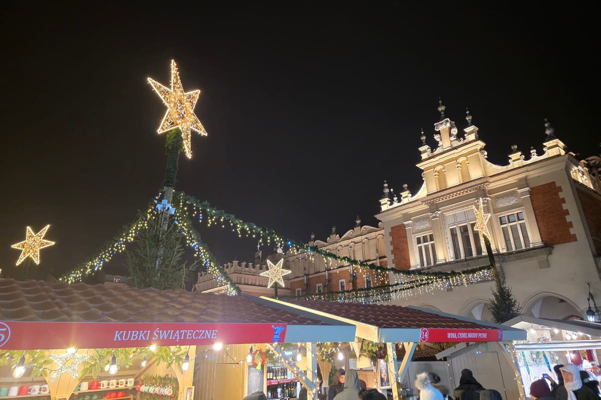 Svetelná hviezda a girlandy nad stánkami pred Sukiennicami večer