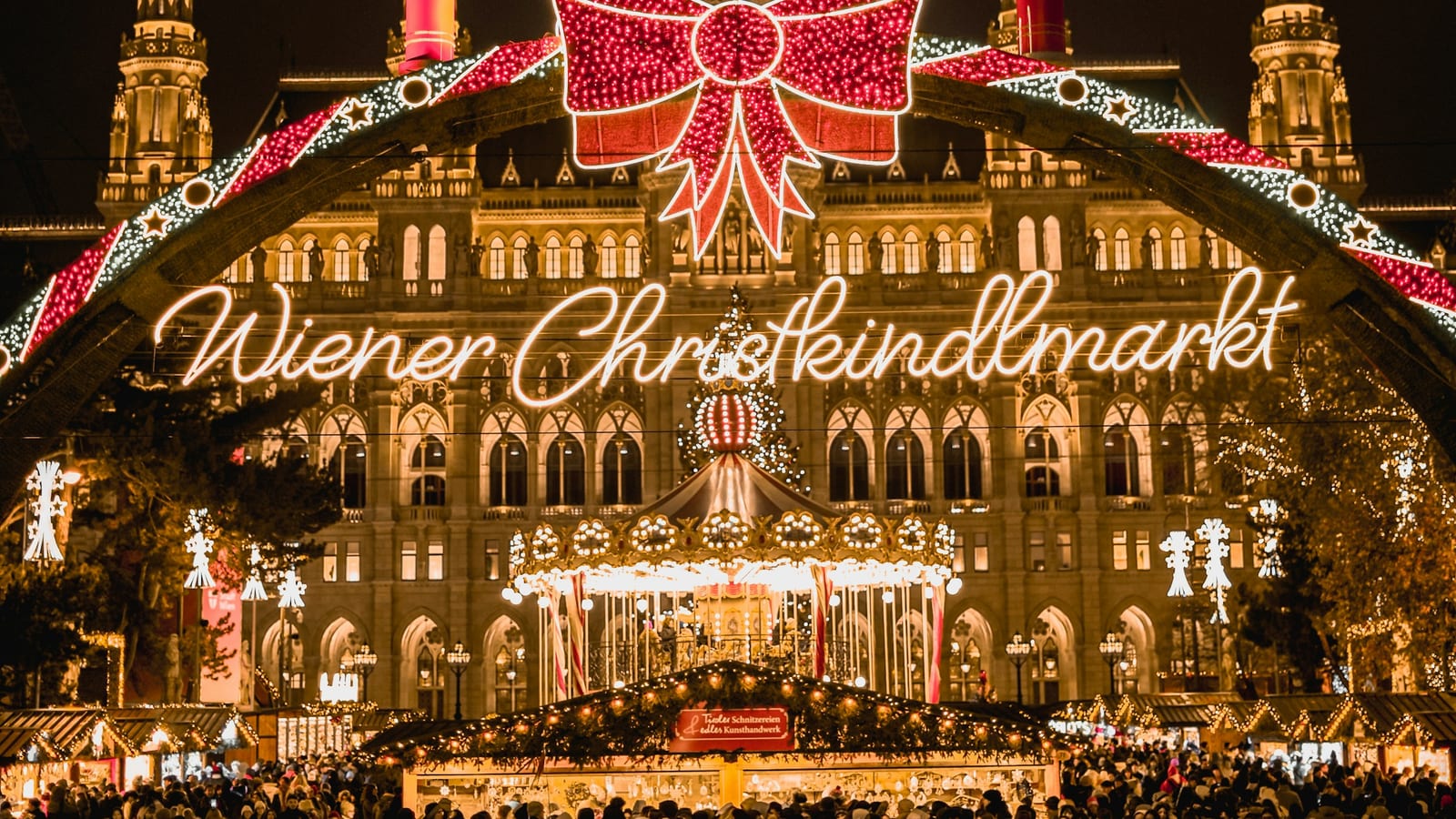 Svetelná brána s nápisom Wiener Christkindlmarkt a osvetlená radnica na Rathausplatz večer