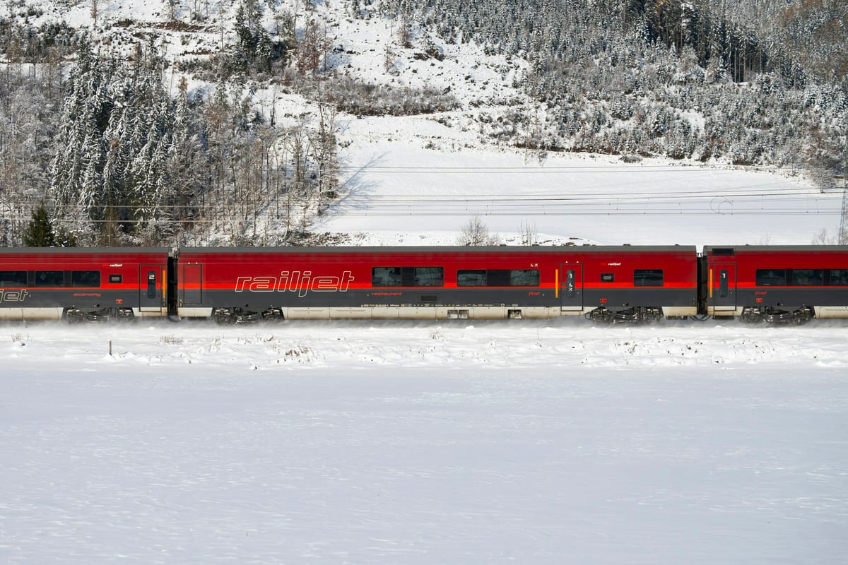 Červený vlak railjet ide zasneženou krajinou