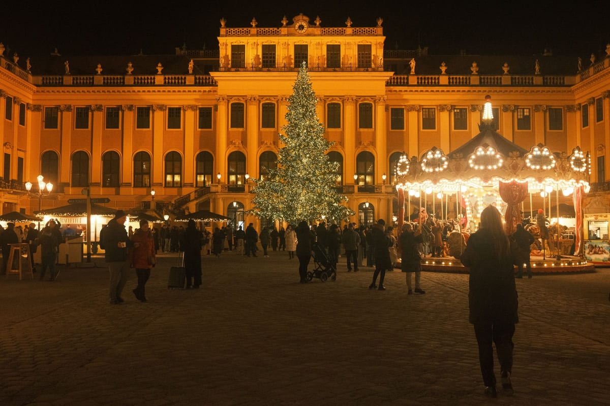 Vianočný stromček, kolotoč a stánky pred zámkom Schönbrunn po zotmení