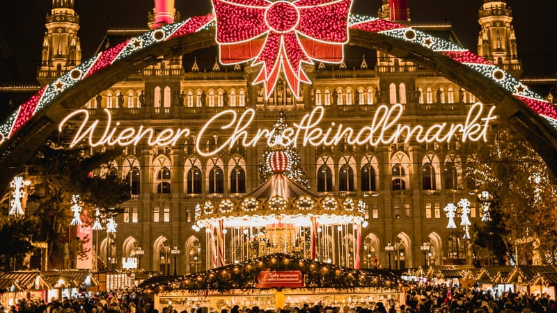 Svetelná brána s nápisom Wiener Christkindlmarkt a osvetlená radnica na Rathausplatz večer