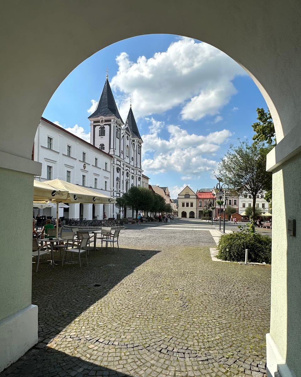 Pohľad z oblúka podlubia na Mariánske námestie a dvojvežový Kostol sv. Pavla apoštola.
