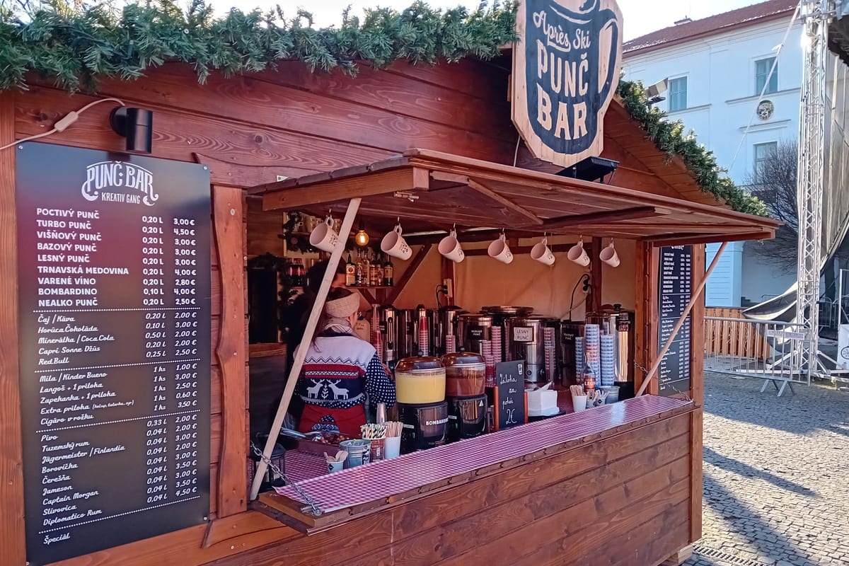 Drevený stánok Punč Bar s tabuľou cien punču a medoviny na vianočných trhoch v Žiline.