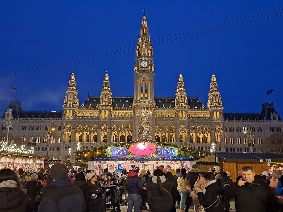 Osvetlená viedenská radnica a stánky vianočných trhov na Rathausplatz plné ľudí