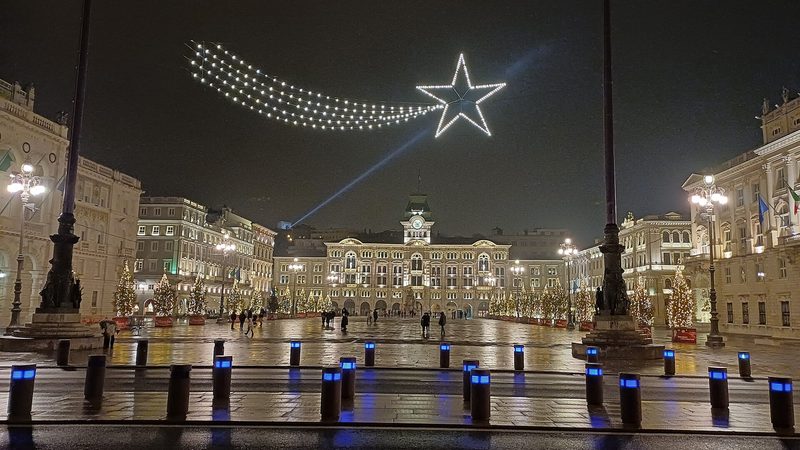 Rozsvietená vianočná kométa nad námestím Piazza Unità d'Italia v Terste po zotmení