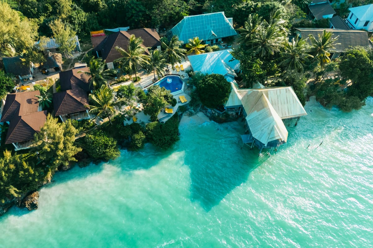 Hotel s bungalovmi a bazénom pri tyrkysovom mori na Zanzibare z výšky