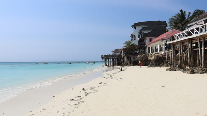 Biela piesočná pláž v Nungwi na severe Zanzibaru s hotelmi na nízkom útese