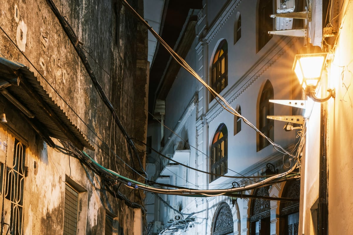 Úzka ulička v Stone Town večer, so schodmi a osvetlenými dverami starých domov
